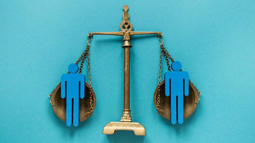 Eine klassische Waage mit zwei Waagschalen, auf denen jeweils eine blaue Figur steht, die Menschen symbolisiert. Die Waage ist in einem ausgewogenen Zustand, was für Gleichberechtigung, Fairness und ethisches Handeln steht. Der blaue Hintergrund unterstreicht das Thema Gleichbehandlung und ethische Standards. Das Bild repräsentiert den Verhaltenskodex und die Werte von Gatzsch Schweißtechnik in Bezug auf faire Arbeitspraktiken und gleiche Chancen für alle.